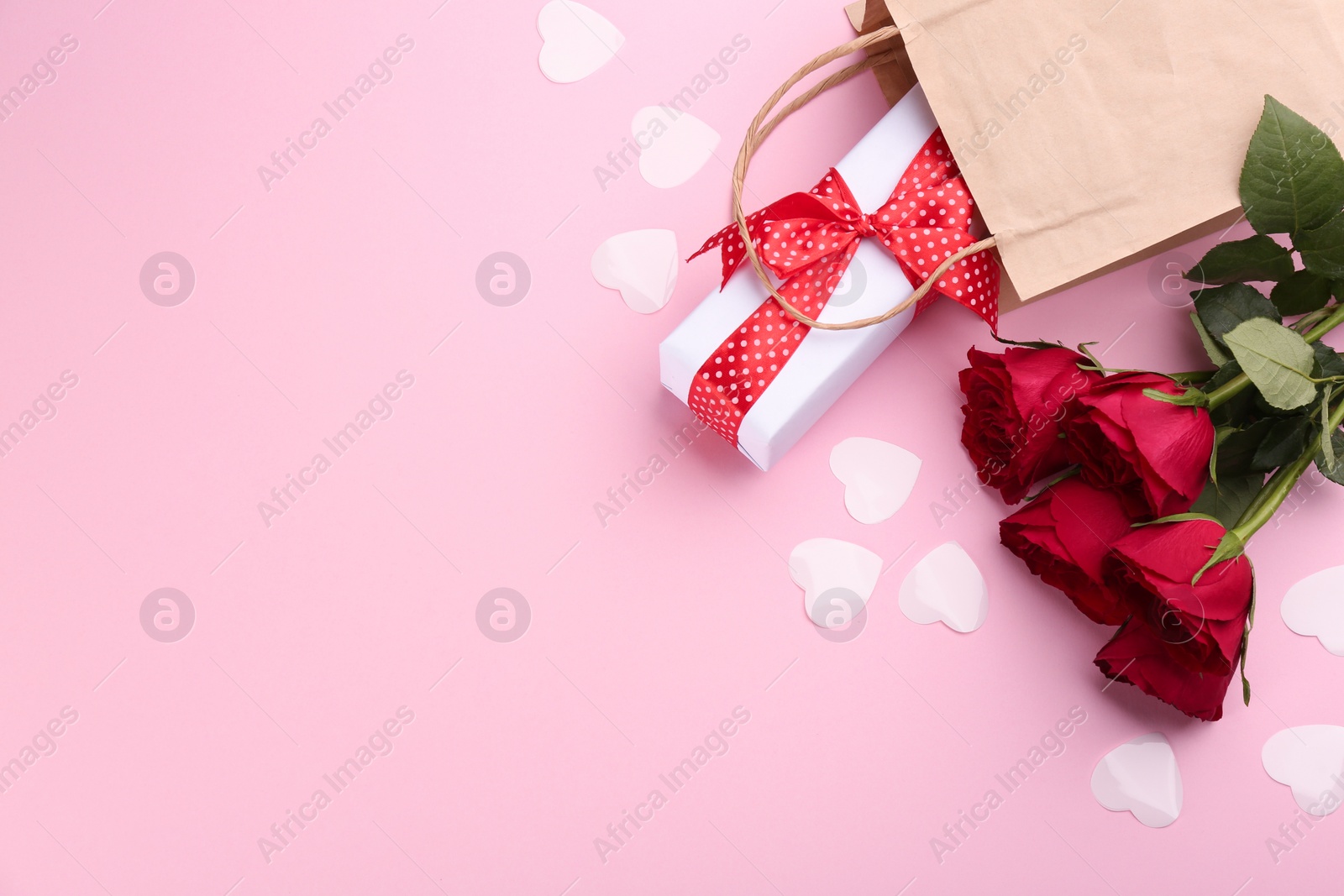 Photo of Beautiful gift box, roses and hearts on pink background, flat lay with space for text. Valentine's day celebration