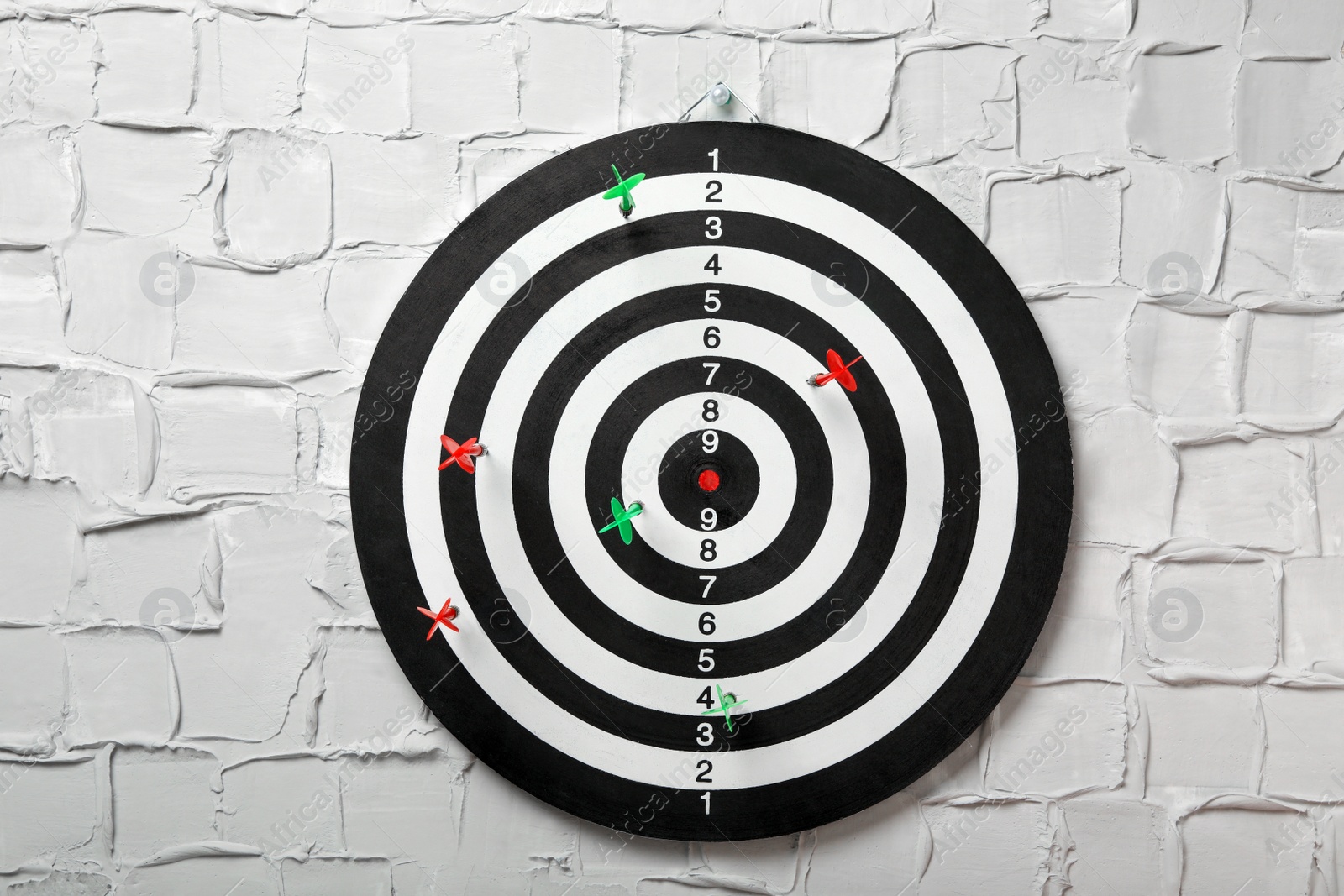 Photo of Arrows hitting dart board on white textured wall