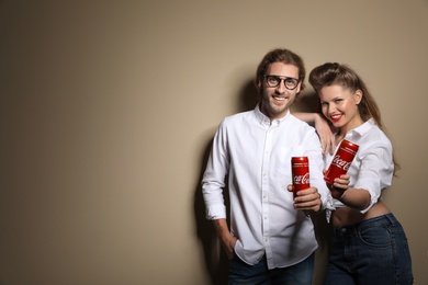 Photo of MYKOLAIV, UKRAINE - NOVEMBER 28, 2018: Young couple with Coca-Cola cans on color background, space for text
