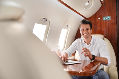 Image of Handsome man working with laptop on  plane. Comfortable flight