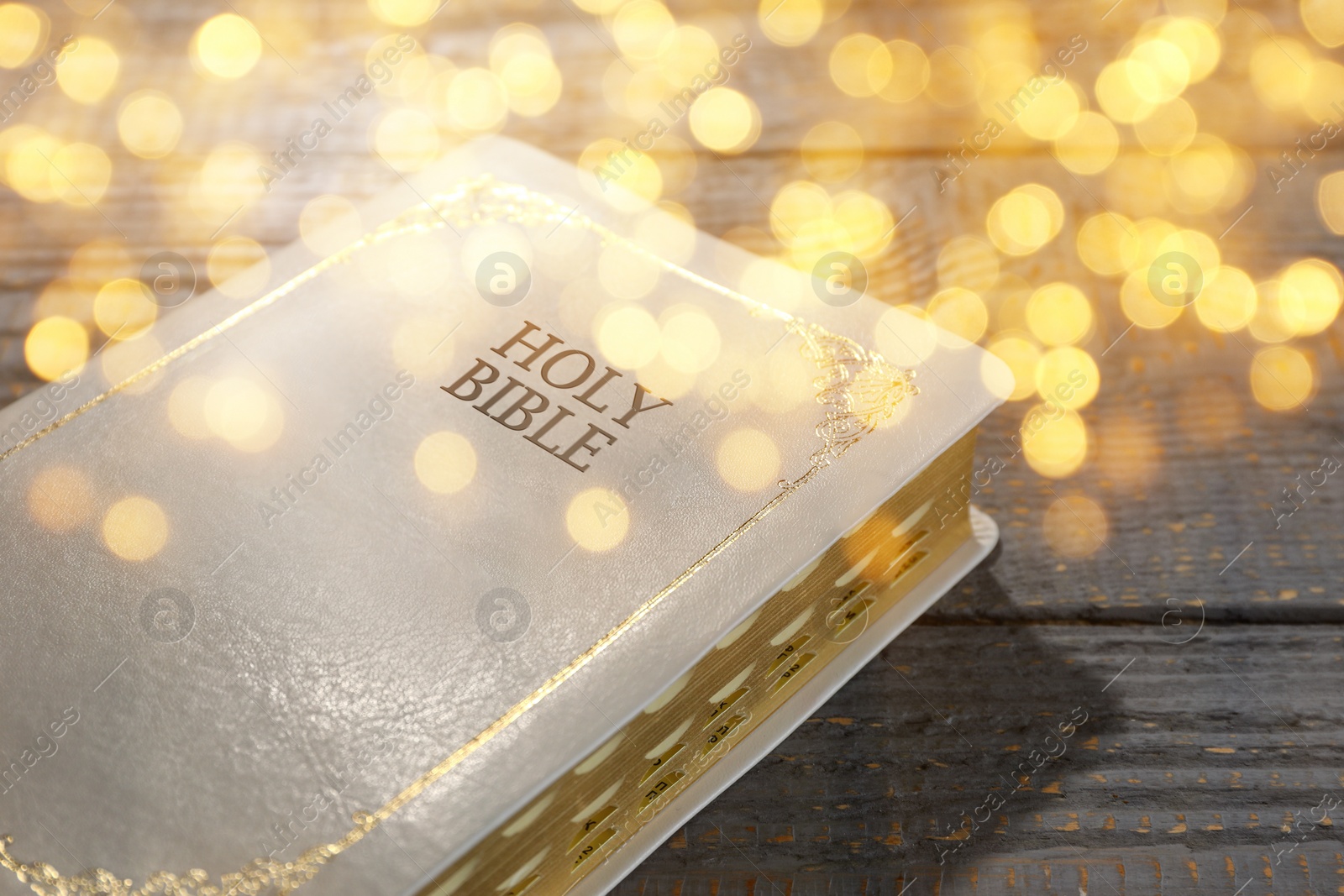 Image of Holy Bible on wooden table, bokeh effect