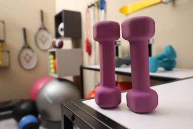Photo of Pink dumbbells on white table in room with other sports equipment