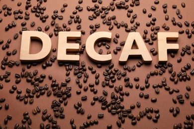 Photo of Word Decaf made of wooden letters on brown background with coffee beans
