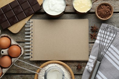 Photo of Blank recipe book surrounded by different ingredients on wooden table, flat lay. Space for text