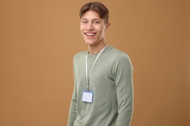 Happy man with blank badge on light brown background