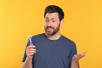 Happy man with tongue cleaner on yellow background