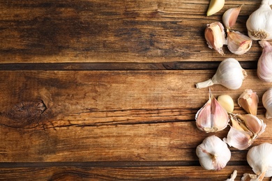 Photo of Fresh organic garlic on wooden table, flat lay. Space for text