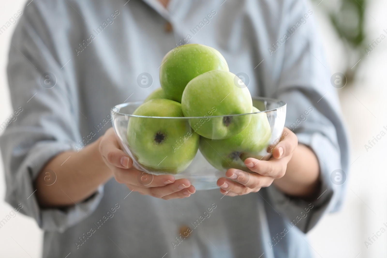 Photo of Woman holding bowl with ripe green apples, closeup