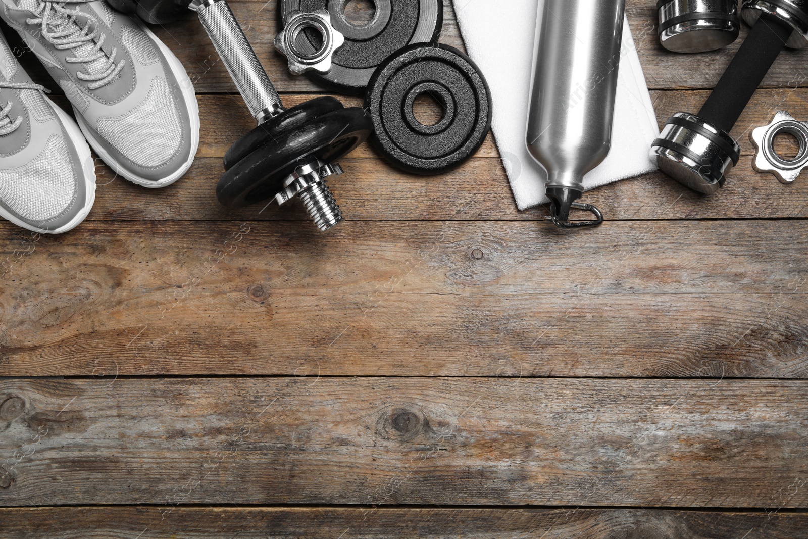 Gym equipment and shoes on wooden background, flat lay. Space for text Photo of Gym equipment and shoes on wooden background, flat lay. Space for text