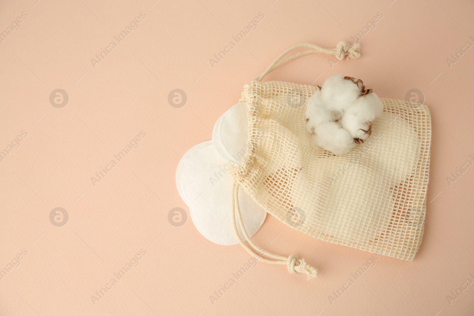 Photo of Bag with cotton pads and flower on beige background, flat lay. Space for text