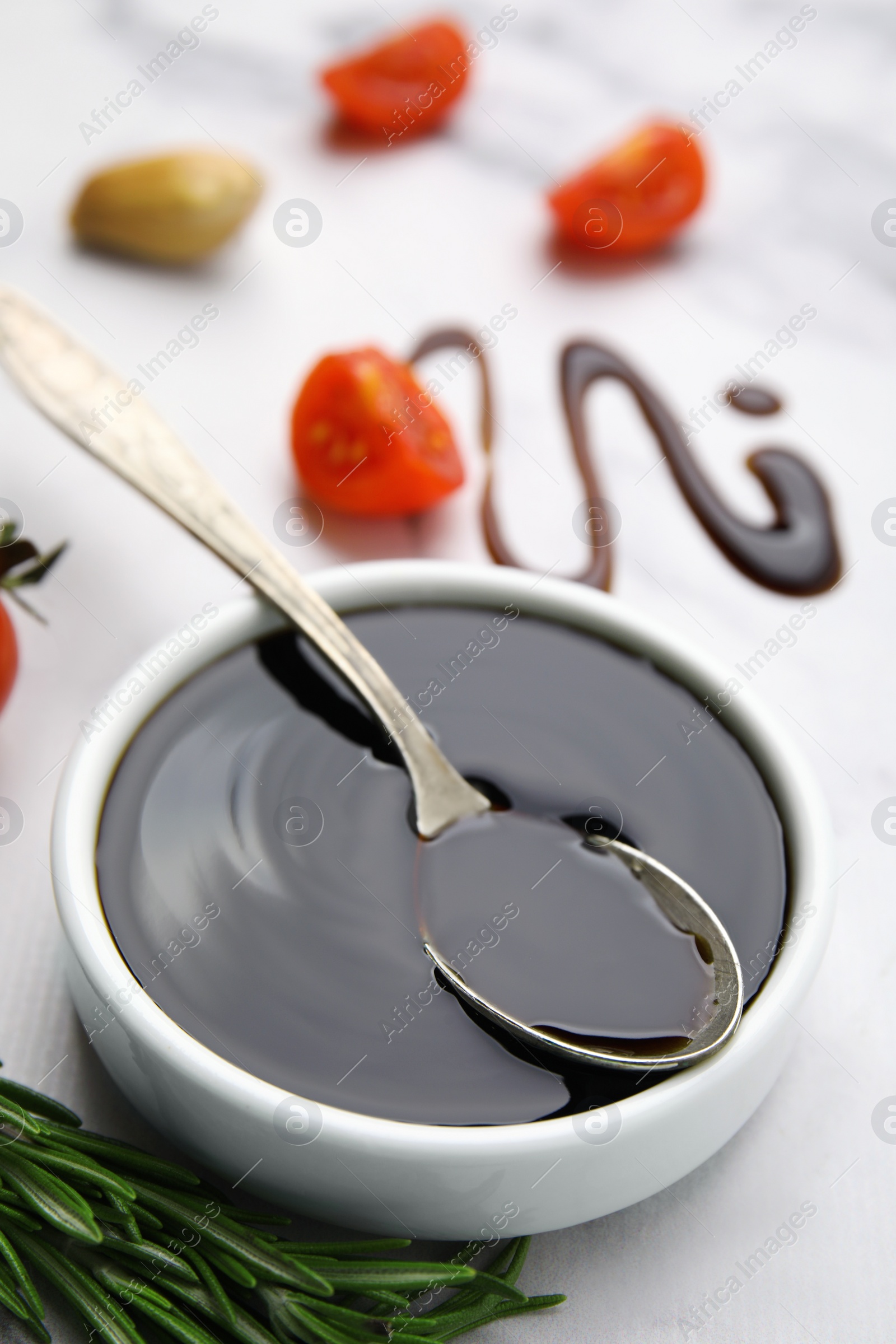 Photo of Organic balsamic vinegar and cooking ingredients on white marble table, closeup