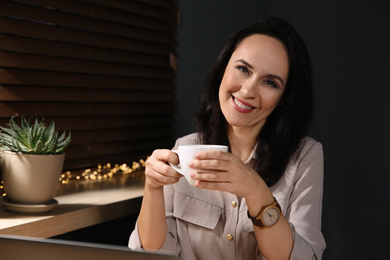 Photo of Beautiful mature woman with cup of coffee at home