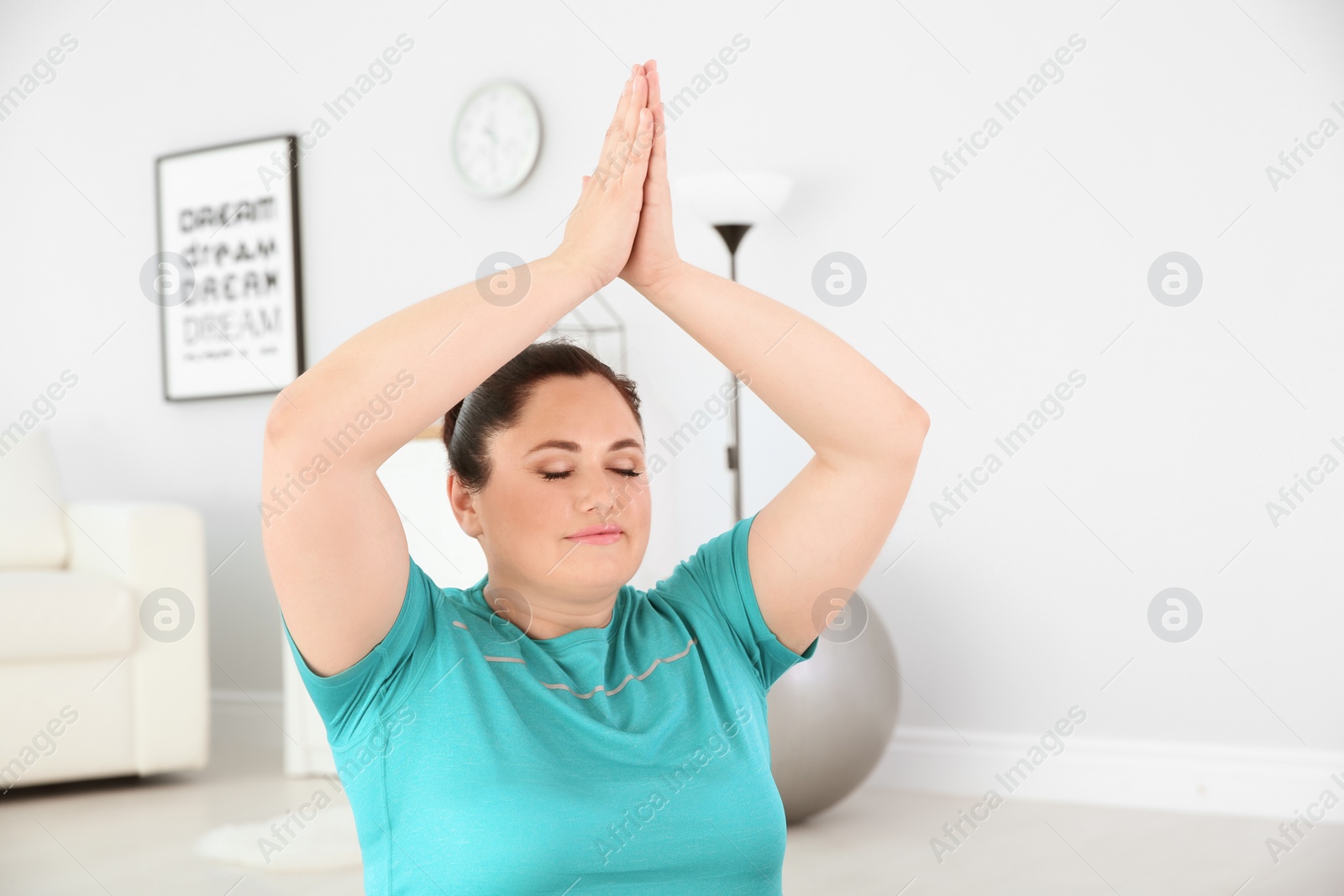 Photo of Overweight young woman practicing yoga at home