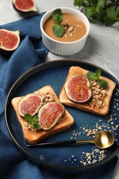 Tasty toasts served with fig, peanut butter and walnuts on light grey marble table, above view