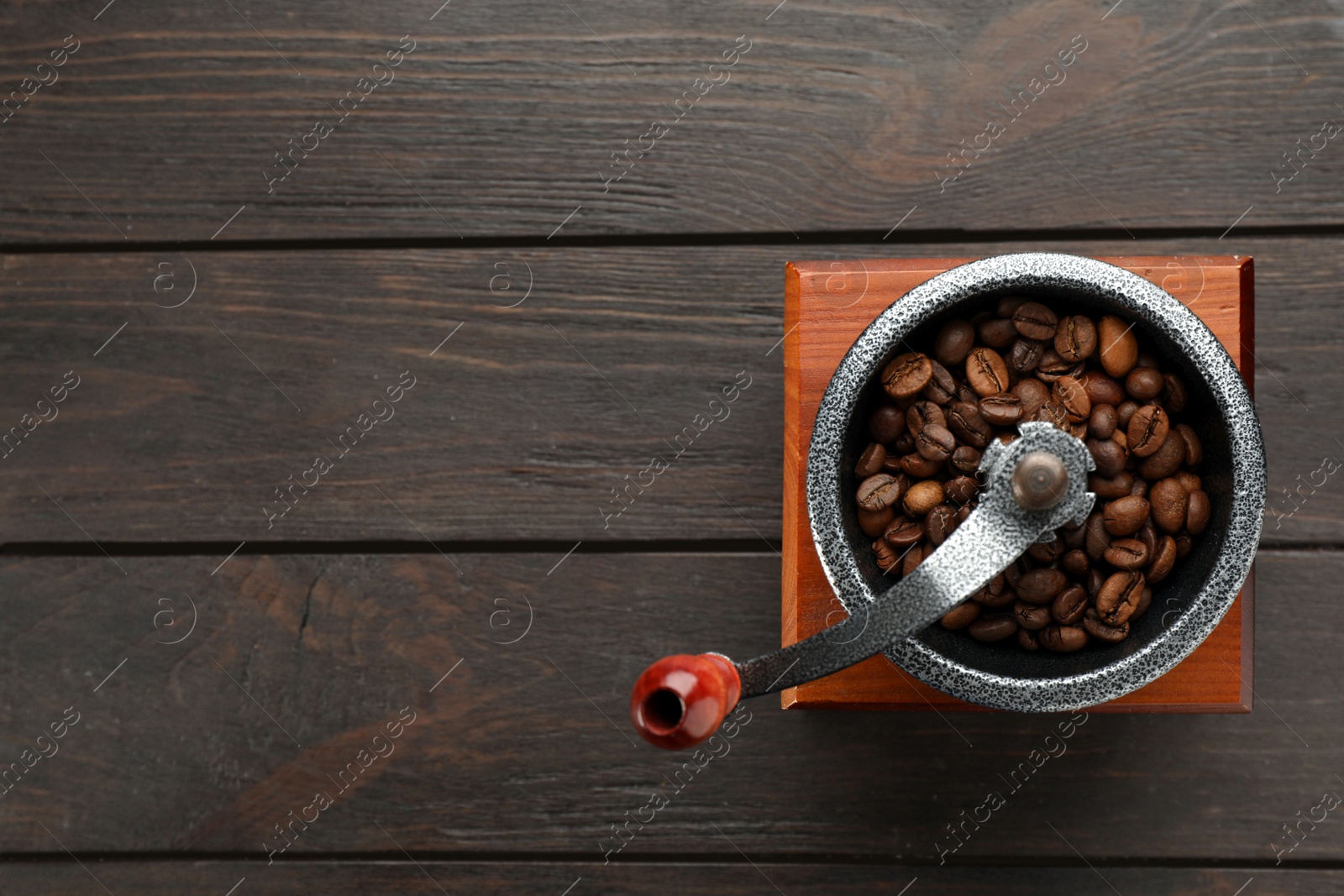 Photo of Vintage manual coffee grinder with beans on wooden table, top view. Space for text