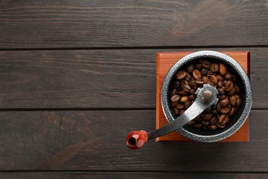 Photo of Vintage manual coffee grinder with beans on wooden table, top view. Space for text