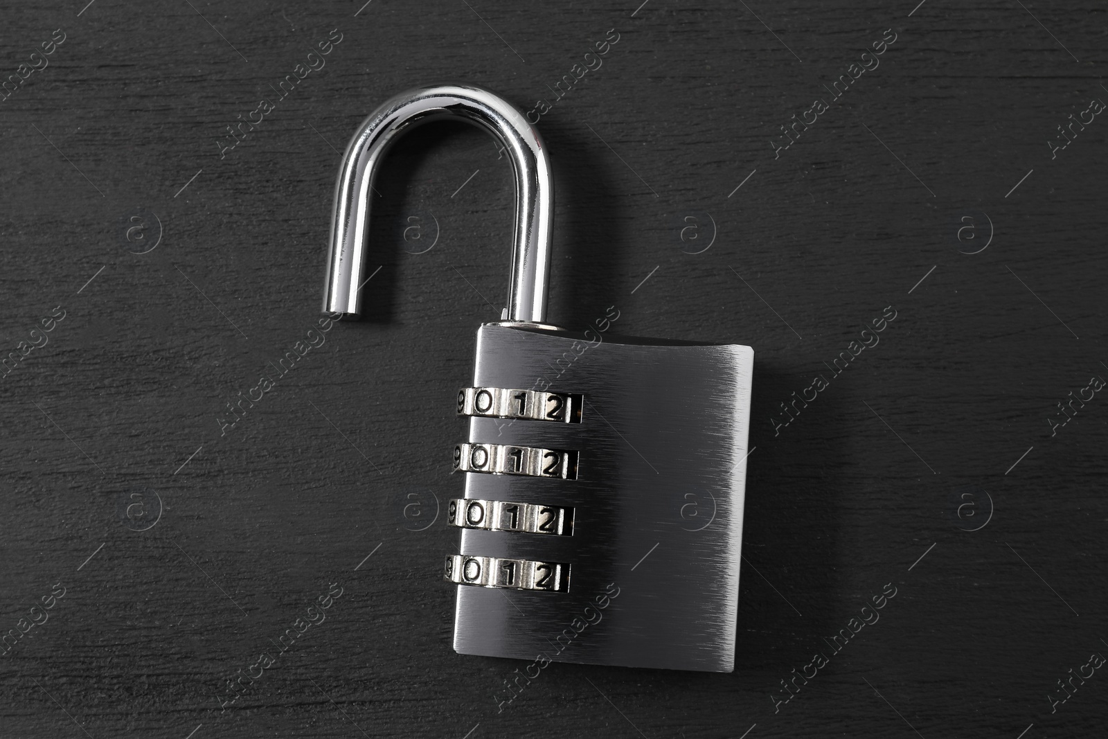 Photo of One steel combination padlock on black wooden table, top view