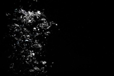 Image of Many air bubbles in water on black background, space for text