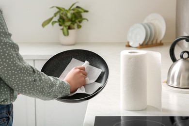 Photo of Woman wiping frying pan with paper towel in kitchen, closeup