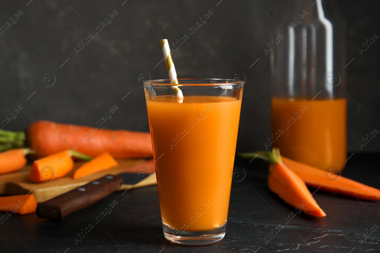 Photo of Glass of freshly made carrot juice on black table