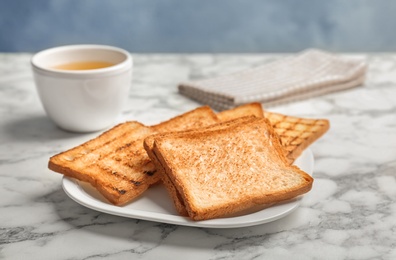 Plate with toasted bread on table