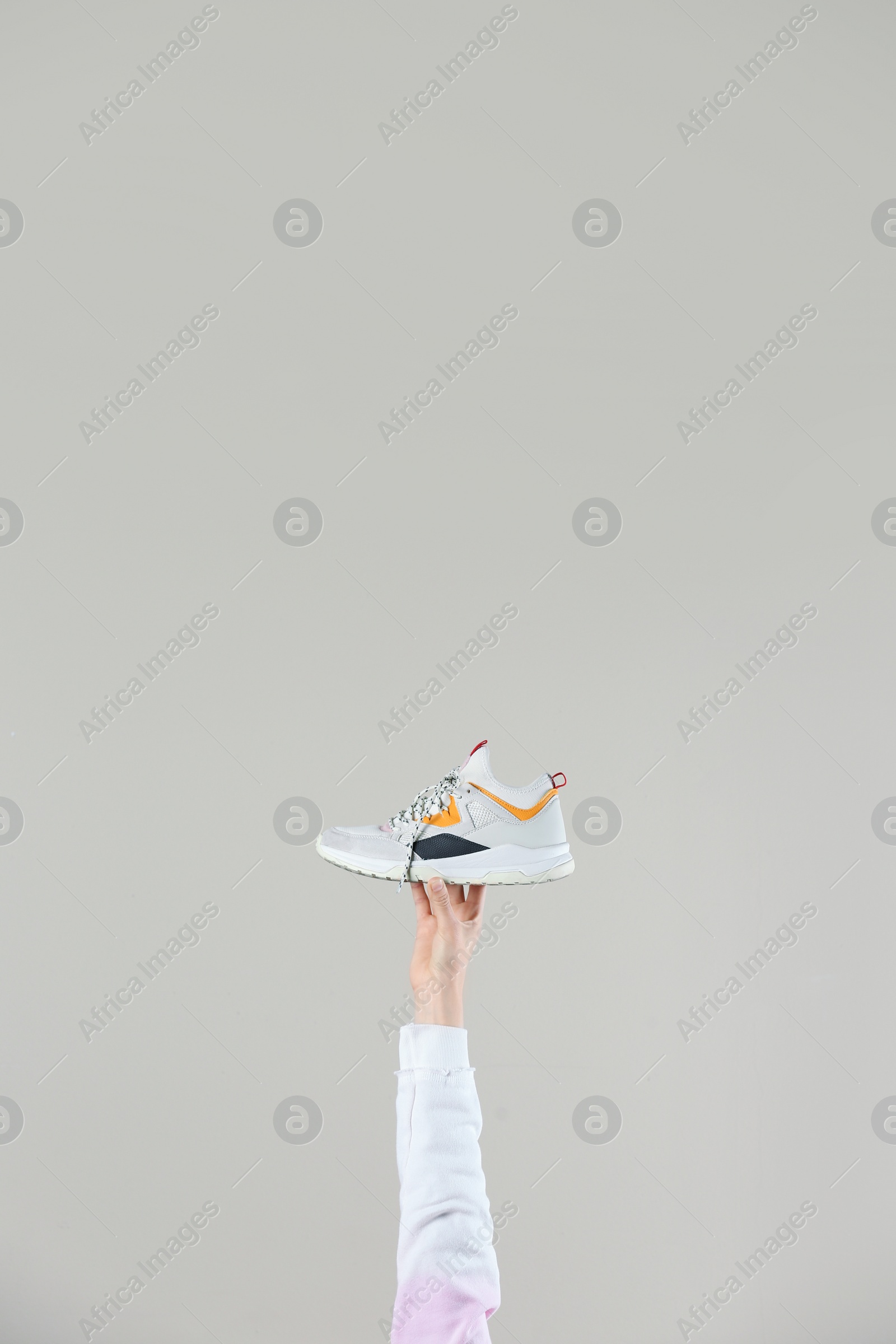 Photo of Woman holding sportive shoe on light background, closeup. Space for text