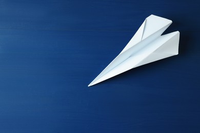 Photo of Handmade paper plane on blue wooden table. Space for text