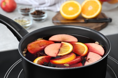 Photo of Delicious hot mulled wine on stove, closeup