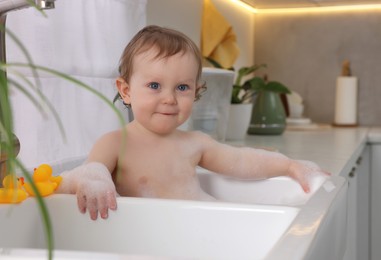 Photo of Cute little baby bathing in sink at home