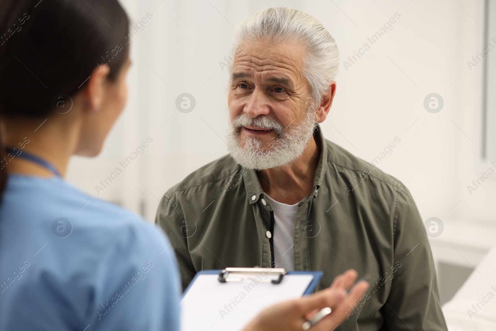 Photo of Elderly patient talking with nurse in hospital