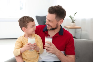 Photo of Father and son with glasses of milk in living room