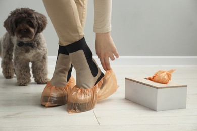 Woman wearing bright shoe covers onto her boots indoors, closeup