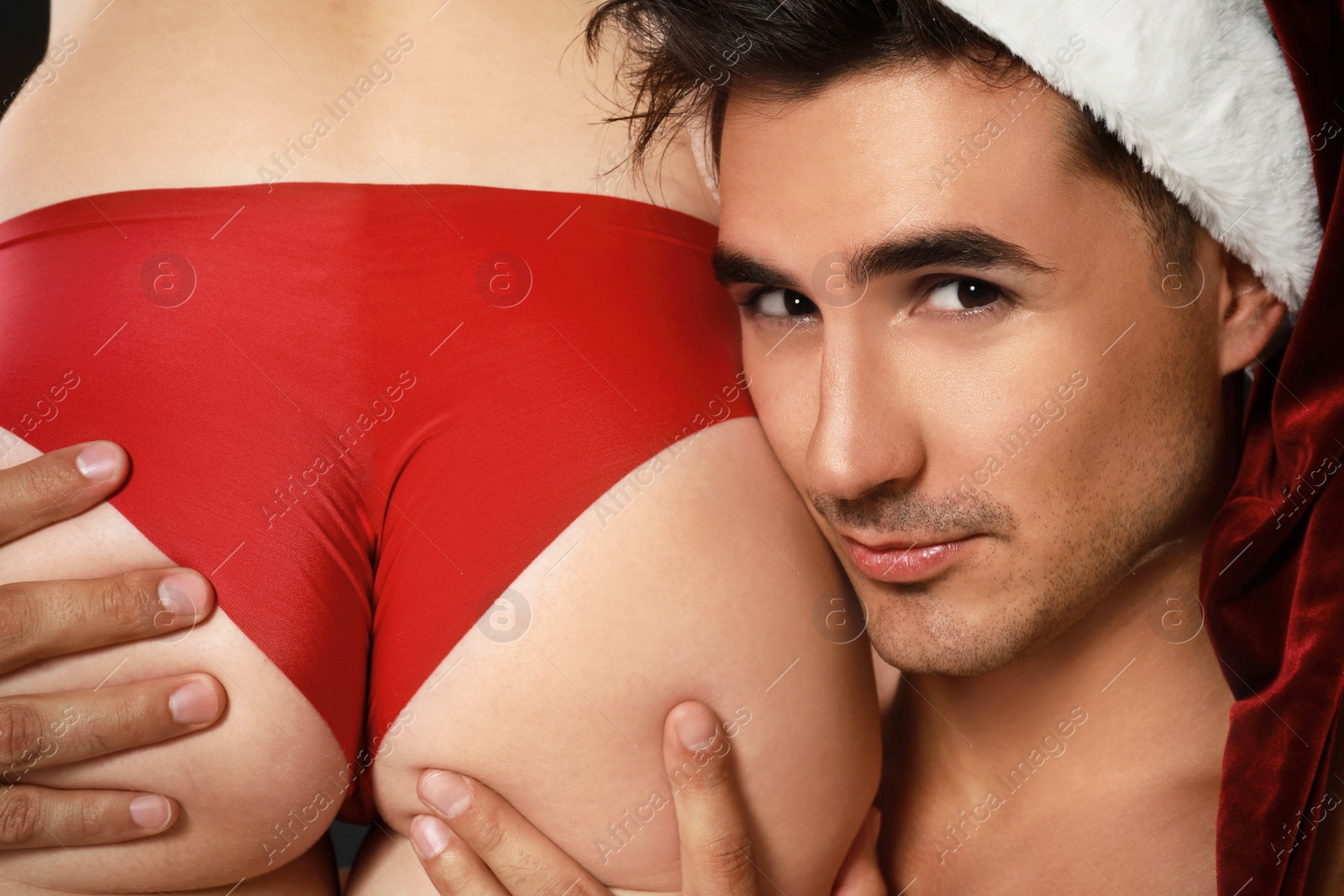 Photo of Attractive young Santa Claus with sexy woman, closeup
