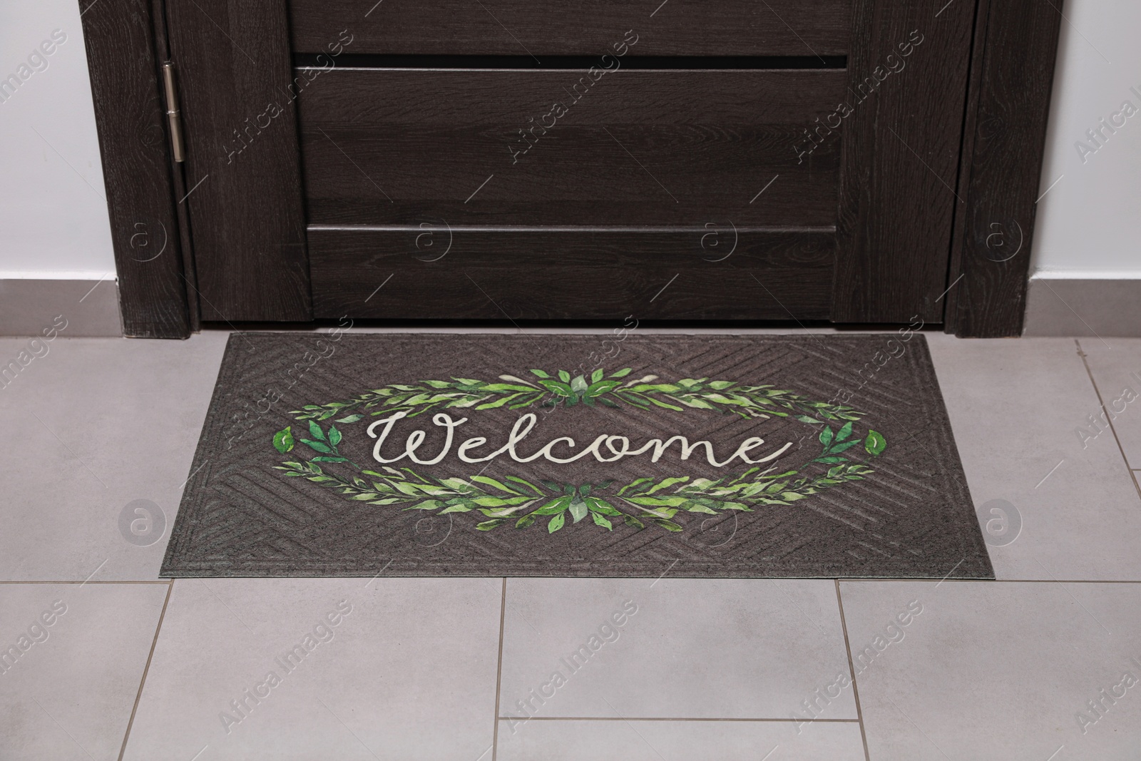 Photo of Beautiful doormat with word Welcome on floor near entrance