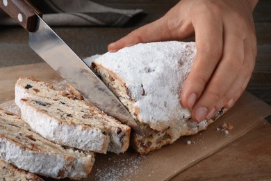 Photo of Woman cutting traditional Christmas Stollen at wooden board, closeup