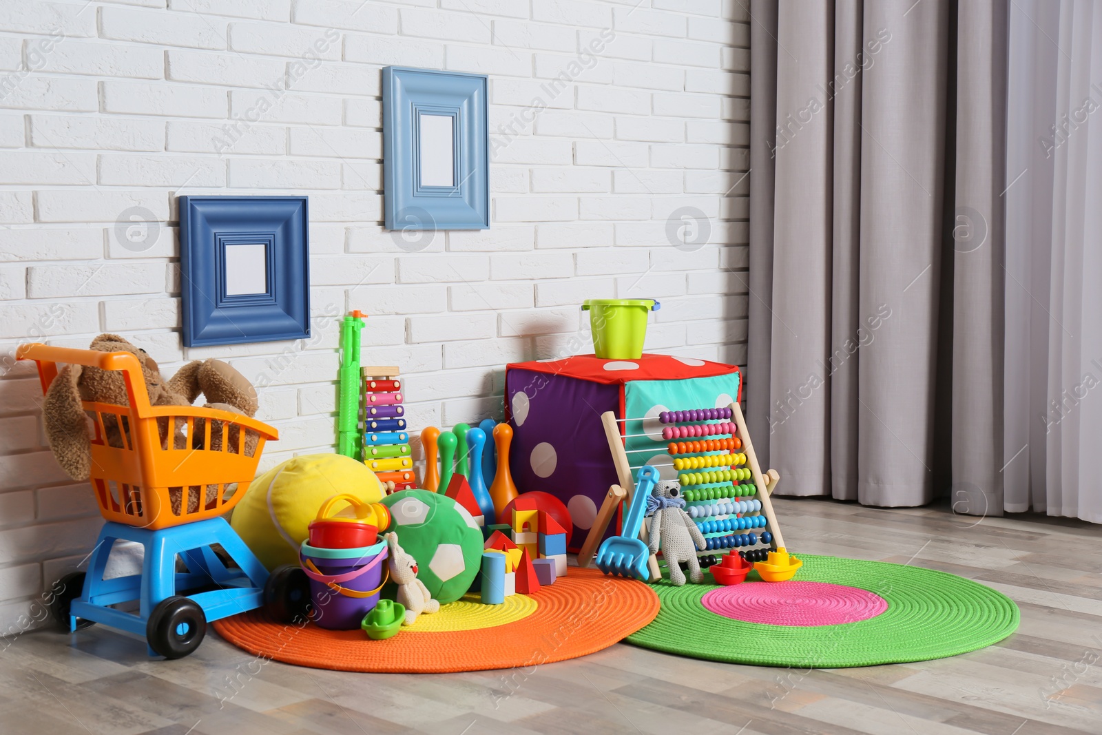 Photo of Different child toys on floor against brick wall