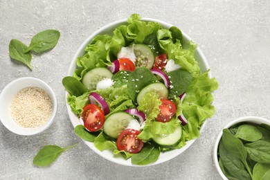 Delicious salad in bowl on light grey table, flat lay