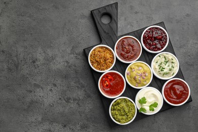 Photo of Different tasty sauces in bowls on grey table, top view. Space for text