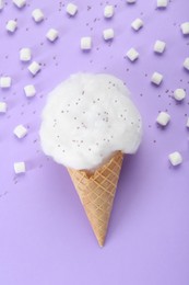 Sweet cotton candy in waffle cone and marshmallows on purple background, flat lay