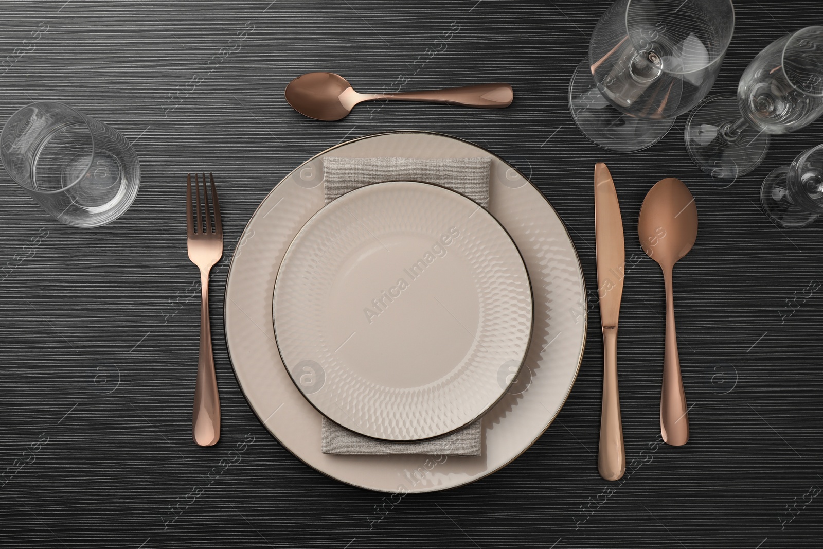 Photo of Stylish setting with cutlery, glasses and plates on black wooden table, flat lay