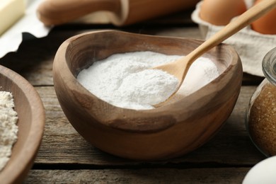 Photo of Baking powder and other ingredients for making dough on wooden table, closeup