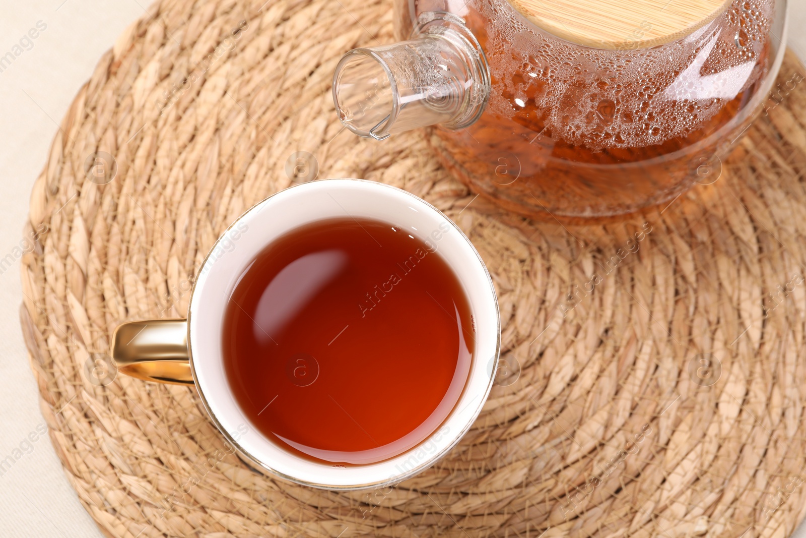 Photo of Aromatic tea in cup and teapot on table, top view