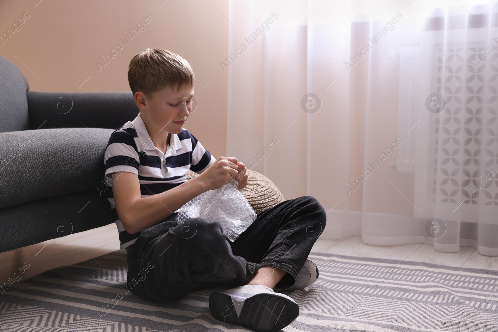 Photo of Boy popping bubble wrap at home. Stress relief