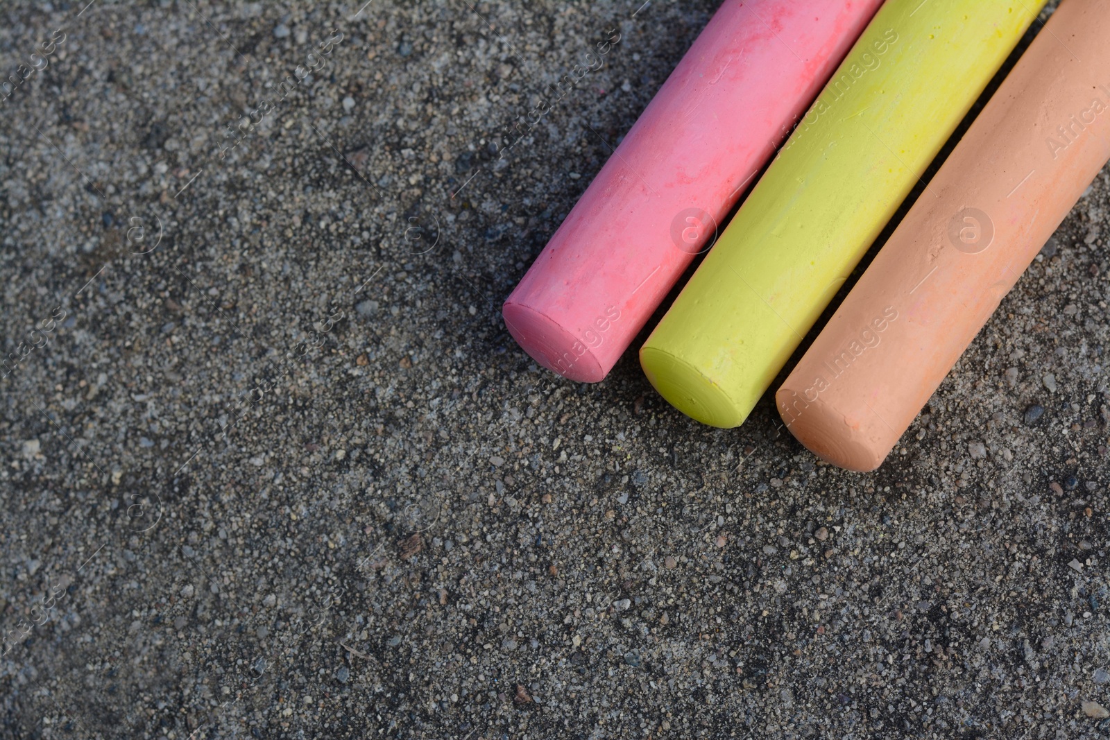 Photo of Colorful chalk sticks on asphalt, flat lay. Space for text