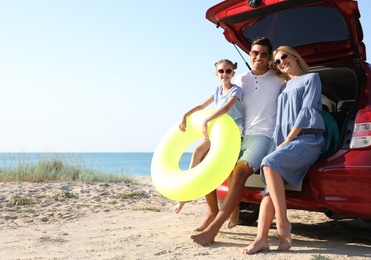 Photo of Happy family with inflatable ring near car at beach on sunny day