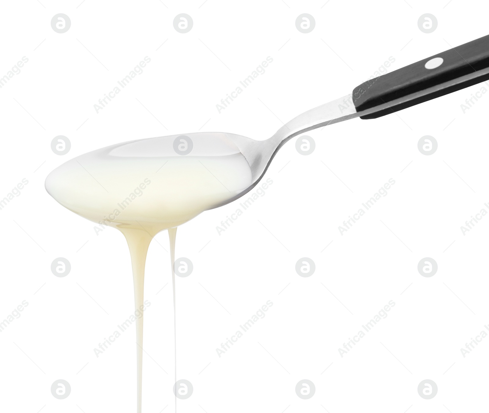 Photo of Pouring condensed milk from metal spoon isolated on white