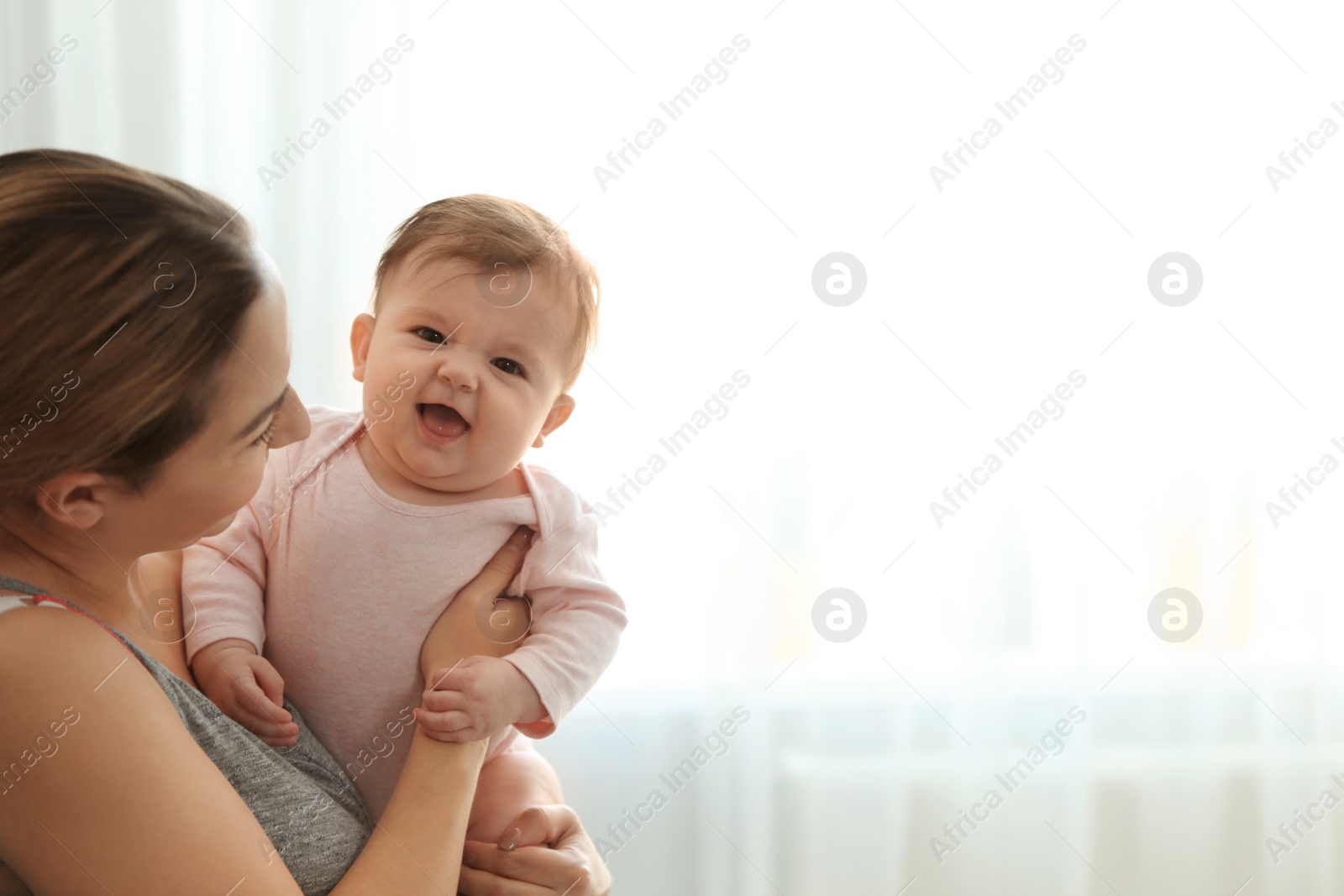 Photo of Young woman with her cute baby at home. Space for text