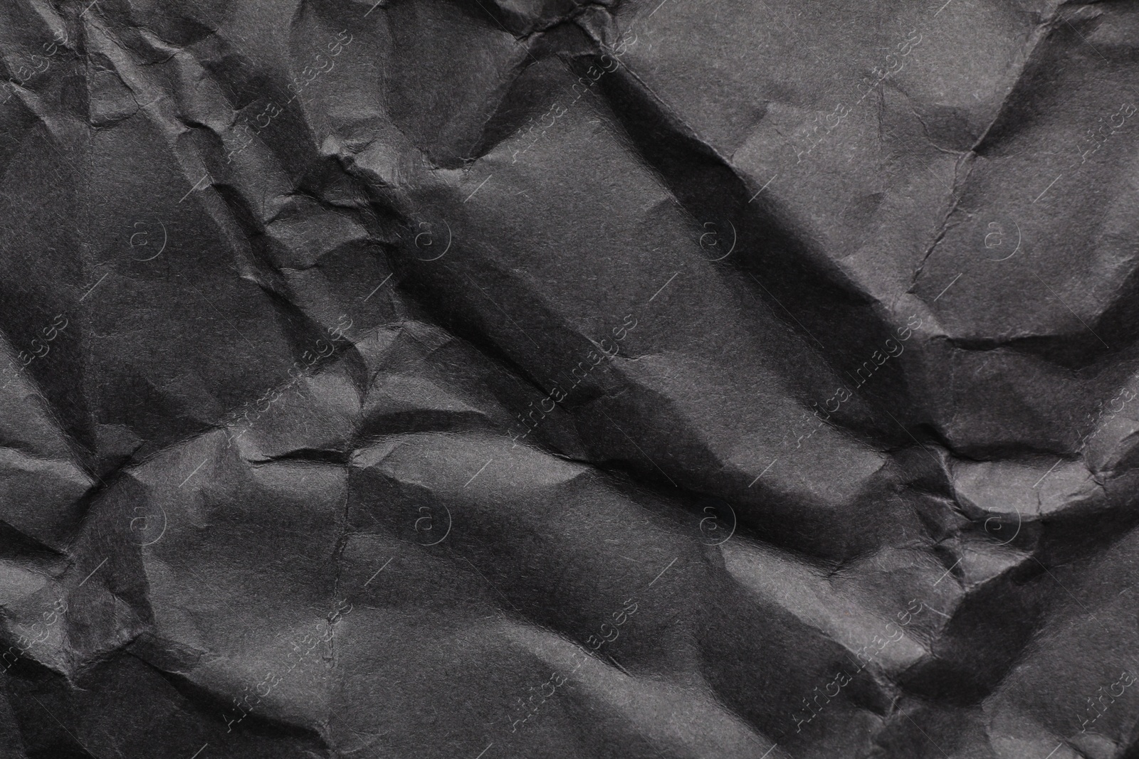 Photo of Sheet of black crumpled paper as background. Space for design