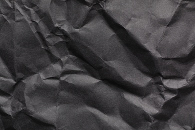 Sheet of black crumpled paper as background. Space for design