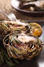 Tasty grilled artichoke served on table, closeup